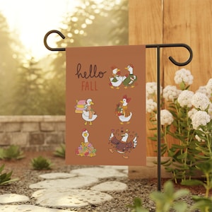 Könnte beinhalten: Eine rechteckige Gartenflagge mit einem rostorangen Hintergrund und dem Schriftzug "hello FALL" in dunkelbrauner Schreibschrift. Das Design zeigt sechs Illustrationen von weißen Enten mit Schals und Pullovern, umgeben von Herbstblättern und Büchern.