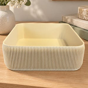 May include: A rectangular, cream-colored storage tray featuring a distinct ribbed or fluted texture along its exterior walls. The container has rounded corners and a smooth, flat interior base, presenting a clean, uniform appearance throughout the design.