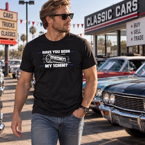 May include: A black short-sleeve t-shirt featuring a graphic of a 10mm socket with technical measurement lines and the text "HAVE YOU SEEN MY 10MM?" printed in white with blue horizontal accent lines across the chest area of the garment.