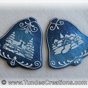 May include: Two blue and white Christmas bells with a winter scene design. One bell features a deer and trees, while the other has a snowy village.