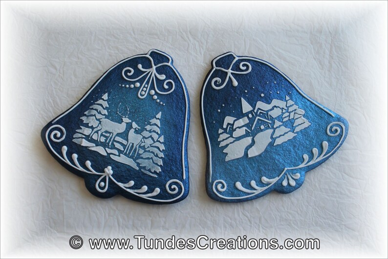 May include: Two blue and white Christmas bells with a winter scene design. One bell features a deer and trees, while the other has a snowy village.