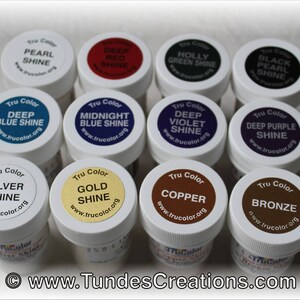 May include: A collection of 10 small, round, white plastic jars with screw-on lids. Each jar contains a different color of paint with a Tru Color label and a website address. The colors include deep blue shine, midnight blue shine, deep violet shine, deep purple shine, silver shine, gold shine, copper, bronze, pearl shine, and deep red shine.