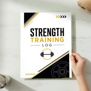 May include: A white strength training log book cover featuring black and gold geometric accents, arrows, and a barbell icon. The text reads STRENGTH TRAINING LOG in bold black and gold lettering, centered on the front of the rectangular notebook.