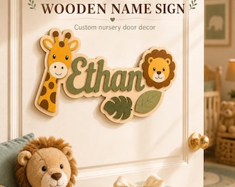 Può includere: Una targa in legno con il nome Ethan in corsivo verde scuro, affiancato da una giraffa gialla e un leone marrone. La targa include due foglie verdi ritagliate e il testo PERSONALIZED WOODEN NAME SIGN Custom nursery door decor.