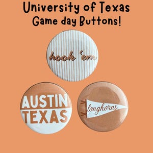 May include: Three circular pin-back buttons with University of Texas themes. One features white stripes and the text hook 'em. Another displays AUSTIN TEXAS in white and burnt orange. The third shows a white pennant with the word longhorns.