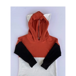 May include: A red, black and white hooded sweatshirt with fox ears on the hood.