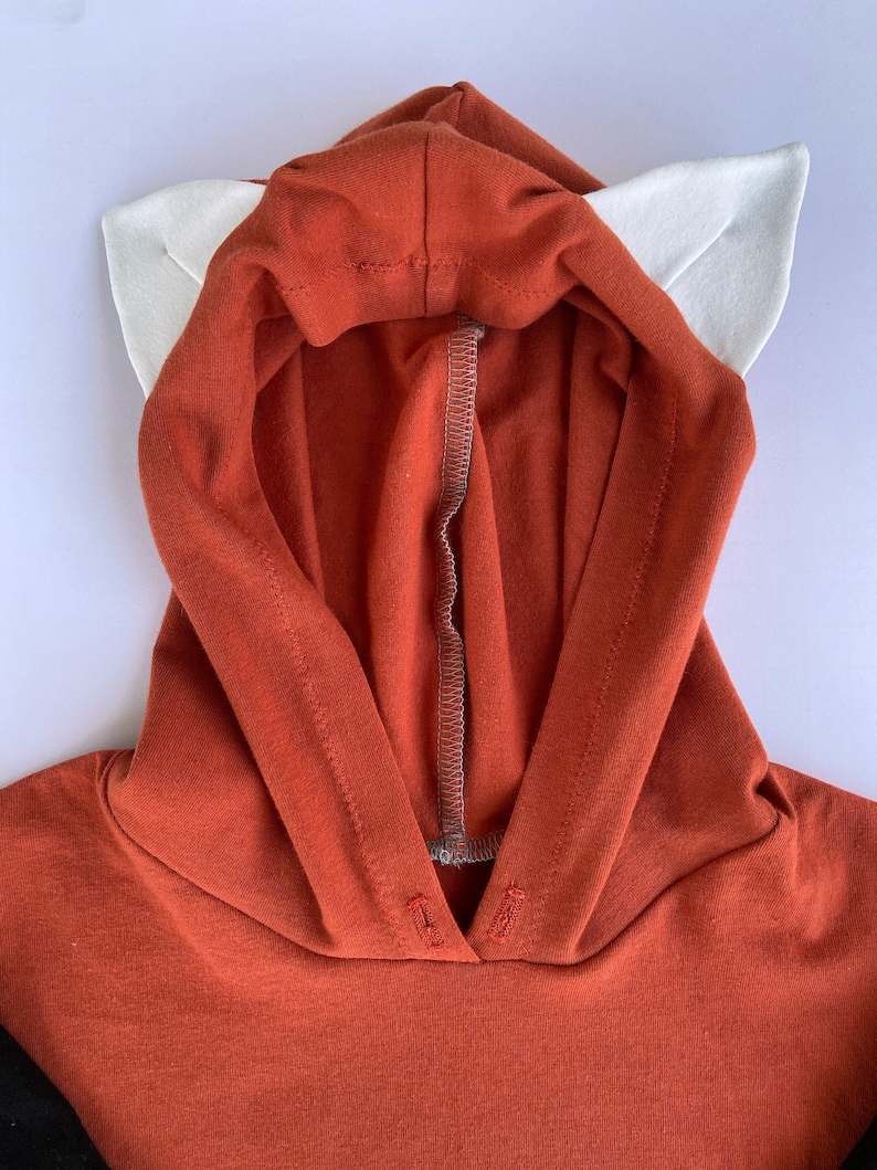 May include: A red hooded sweatshirt with white ears attached to the hood. The sweatshirt is made of a soft, comfortable fabric.
