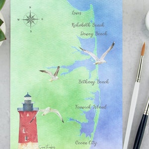 May include: A watercolor painting of a map of the Delaware beaches, including Lewes, Rehoboth Beach, Dewey Beach, Bethany Beach, Fenwick Island, and Ocean City. The map features a red lighthouse and seagulls flying overhead.