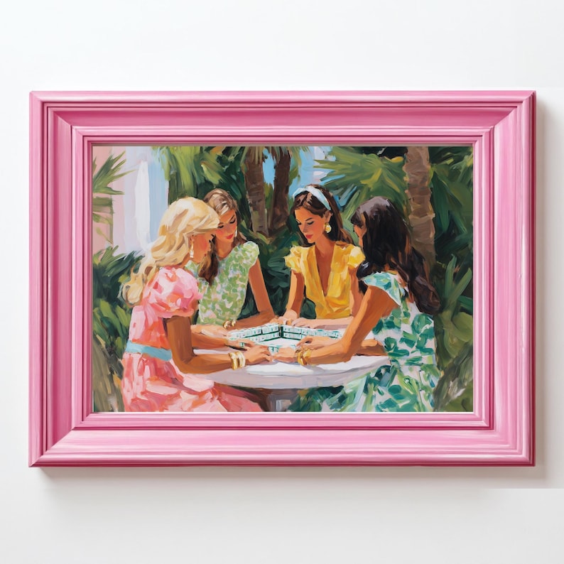 May include: A framed painting depicts four women playing a game at a white table, surrounded by lush greenery. The women wear colorful dresses in shades of pink, yellow, and green. The painting is enclosed in a bright pink frame.