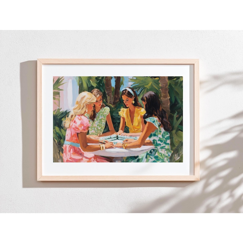 May include: A framed art print depicts four women gathered around a table, playing a game. The women are dressed in colorful dresses, with a lush green tropical background. The artwork is framed in a light wood frame, adding a touch of elegance to the scene.