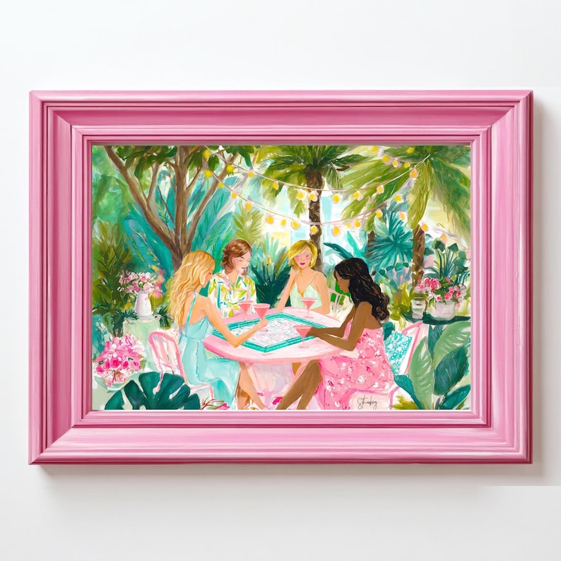 K&ouml;nnte beinhalten: Ein gerahmter Kunstdruck, der vier Personen zeigt, die an einem runden rosa Tisch in einem &uuml;ppigen tropischen Garten sitzen und ein Brettspiel spielen, mit Lichterketten, leuchtend gr&uuml;nem Laub und rosa Blumenakzenten, eingefasst in einen rosa Rahmen.
