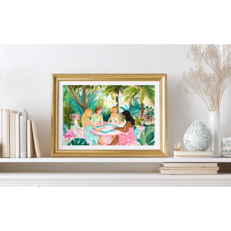K&ouml;nnte beinhalten: Ein gerahmter Kunstdruck mit einer Aquarellillustration von vier Personen, die an einem runden Tisch in einem &uuml;ppigen tropischen Garten sitzen. Die Szene zeigt sattes gr&uuml;nes Laub, rosa Blumen, Lichterketten und ein Brettspiel auf dem Tisch.