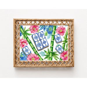 May include: A framed print featuring a watercolor design with bamboo stalks, pink and blue flowers, and blue and white tiles. The frame is made of woven light brown material.