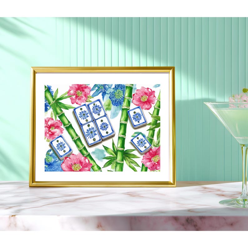 May include: A framed art print featuring a watercolor design of bamboo stalks, pink and blue flowers, and dominoes. The dominoes have a blue and white floral design. The frame is gold.
