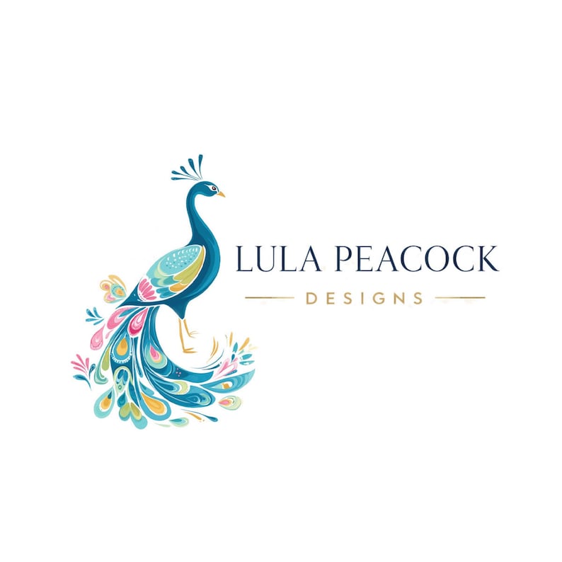 May include: A colorful peacock illustration with a blue body, teal wings, and a vibrant tail featuring pink, yellow, and blue accents. The text "LULA PEACOCK DESIGNS" is displayed in navy blue with gold lines.