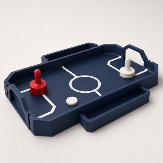 Rear-right close-up of the Dark Blue RinkRush table hockey game showing raised rails, angular goals, two pushers, and one puck
