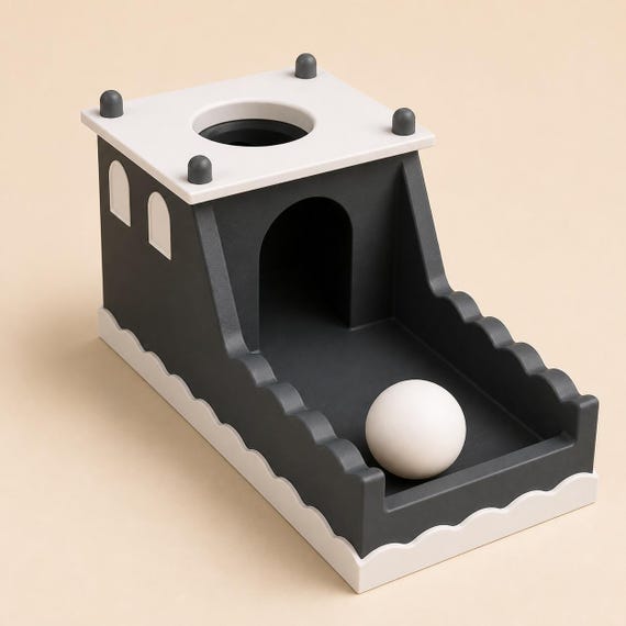 Midnight Castle ball drop box in charcoal, ivory, and gray from a close front-left view with one ball in the tray.