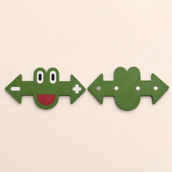 Front and back views of a green frog marker showing four circular magnetic inserts across the reverse side.