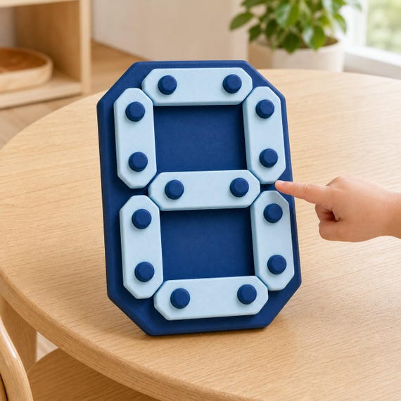 Child pointing to the center bar of an Ocean Contrast DigitPath number board on a light wood learning table.