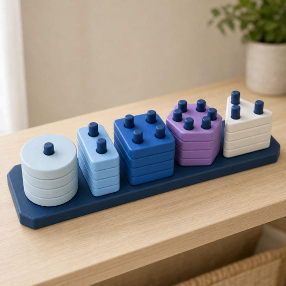 Ocean Trail ShapeHarbor counting peg puzzle in light and deep blues, lilac, and ivory on a pale wood shelf, front-right view.
