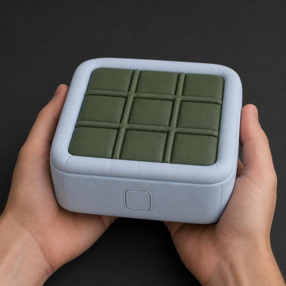 Close-up of the closed PuffGrid game held in two hands to show its portable scale