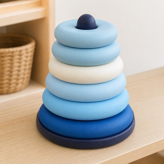 Ocean Drift RingRise sequencing tower with six blue, ivory, and ice-blue rings on a dark blue base, close-up right-side view on a pale wood shelf.