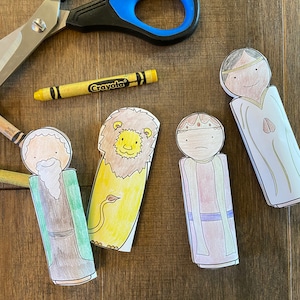 May include: A set of five paper puppets, including a lion, a king, a queen, and two other figures. The puppets are coloured in with crayons and are ready to be cut out.