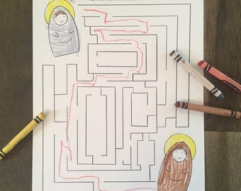 May include: A children's activity sheet featuring a maze with the text "Help Mother Mary visit St. Elizabeth. Then color the saints." The maze is drawn in black ink, with a red crayon path. Crayons in yellow, brown, and red are scattered around.