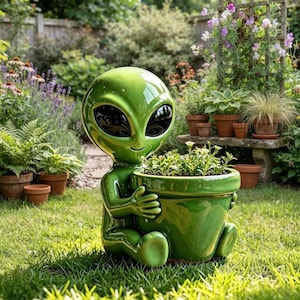 May include: A glossy, bright green ceramic alien figurine sitting on the grass and holding a matching green plant pot. The alien has a large, smooth, rounded head with two expansive, dark, oval-shaped eyes and a small, subtle, smiling mouth.