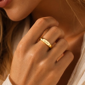Peut inclure: Une bague anneau en or poli présentant une surface lisse et arrondie avec le prénom arabe Maria gravé en écriture noire sur le devant. La bague possède une construction simple et solide ainsi qu'une finition métallique réfléchissante.