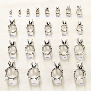 May include: A collection of silver-toned metal pendant settings arranged in rows, each featuring a circular prong setting and a bail. The sizes range from 4mm to 25mm, with each piece clearly labeled with its corresponding metric measurement in blue text.