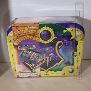 May include: A Harry Potter View-Master collector case with a purple and yellow design, featuring a brick archway graphic and the text Harry Potter Collector Case. A clear ruler shows the case height is approximately 8 inches tall.
