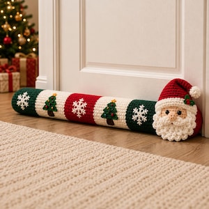 May include: A cylindrical crochet door draft stopper featuring alternating red, white, and dark green panels. The design includes white snowflake motifs and small green Christmas tree appliques. One end is finished with a Santa Claus head.
