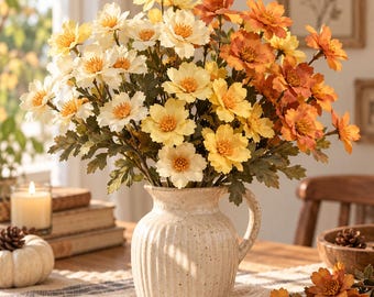 May include: A ceramic pitcher with a cream-colored speckled finish and vertical ribbed texture holds a large bouquet of artificial flowers in shades of white, yellow, and burnt orange, featuring green leaves and prominent yellow centers.