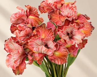 May include: A bouquet of artificial flowers featuring ruffled petals in shades of coral, orange, and cream with delicate white edges. The blooms are attached to green stems with small green leaves, creating a dense, layered floral arrangement.