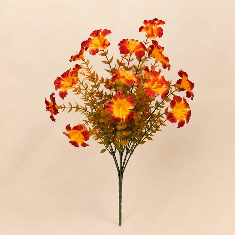 May include: A bouquet of artificial flowers featuring multiple blossoms with vibrant orange and yellow petals. The flowers are attached to thin green stems with small, pointed green leaves, all gathered into a single central stalk at the base.