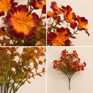 May include: A bouquet of artificial flowers featuring five-petaled blossoms with vibrant orange centers and deep burgundy edges. The stems are thin and green, accompanied by small, pointed, brownish-green leaves throughout the arrangement.