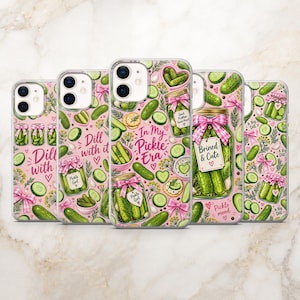 May include: A collection of five smartphone cases featuring a repeating pattern of green pickles, pink gingham bows, and jars. Text includes "Dill with it," "In My Pickle Era," "Brined & Cute," and "Pickle mood" printed in pink script on a light pink background.