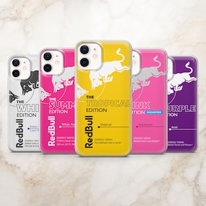 May include: Five smartphone cases featuring Red Bull energy drink designs in white, pink, yellow, pink, and purple. Each case displays the iconic bull logo, the text The Edition, and specific flavor labels like Tropical, White Peach, and Acai.