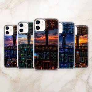 Puede incluir: Cinco fundas transparentes para teléfono con una impresión de alta resolución de la vista desde la cabina de un avión al atardecer. El diseño muestra paneles de instrumentos iluminados, controles de vuelo y una vista panorámica.