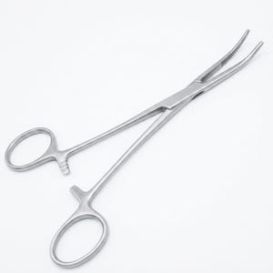 Pode incluir: Uma pinça hemostática de aço inoxidável prateado com pontas curvas e serrilhadas, e um mecanismo de travamento de catraca perto dos anéis. O instrumento cirúrgico apresenta uma haste longa e fina com dois cabos ovais para operação manual.