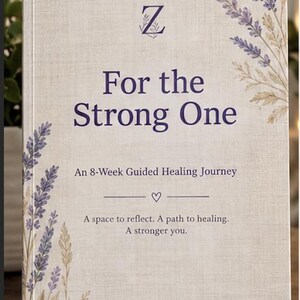May include: A book with a light beige textured cover featuring purple lavender illustrations. The title reads "For the Strong One" with the subtitle "An 8-Week Guided Healing Journey" and the text "A space to reflect. A path to healing. A stronger you."