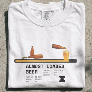 Puede incluir: Una camiseta blanca con un gráfico de una barra de carga con botellas de cerveza y un vaso de cerveza. El texto dice ALMOST LOADED BEER, CONTROL OUTPUT VERSION V2.3, PART NO AC-6488, SERIAL 00258-M, REV R3, STEP/DIR DUAL, e incluye un icono de reloj de arena.