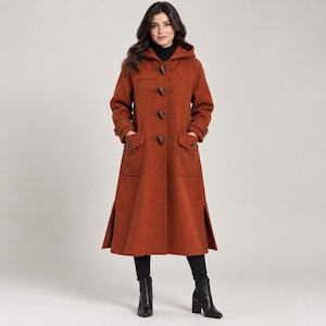 May include: A long, burnt orange wool-blend coat featuring a hood, a high collar, and a front closure with four wooden toggle buttons. The coat includes two large patch pockets with button flaps, long sleeves with cuffs, and side slits at the hem.