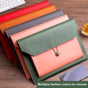 May include: A stack of five rectangular document folders in red, orange, dark grey, light pink, and dark green. Each folder features a pointed flap secured by a thin elastic cord wrapped around a small, circular, textured metal button fastener.