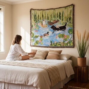 May include: A rectangular woven wall tapestry featuring a colourful illustration of dogs and ducks swimming in a pond with lily pads and green reeds. The scene includes a black dog, a golden dog, and a calico cat, all rendered in a painterly style.