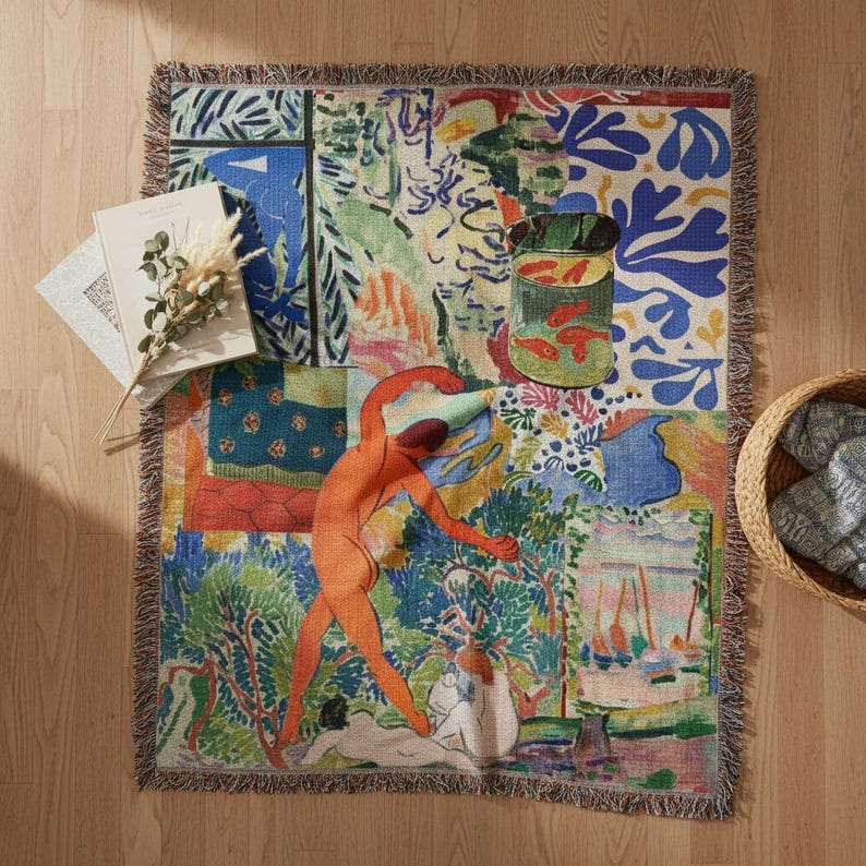 May include: A woven throw blanket featuring a colorful collage of abstract shapes, a green fishbowl with orange fish, and a central orange human figure in a dynamic pose, surrounded by blue, green, and yellow patterns with fringed edges.