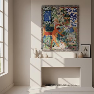 May include: A rectangular woven throw blanket featuring a vibrant, multi-colored collage of abstract shapes, figures, and a goldfish bowl. The tapestry has a fringed edge and displays a complex composition of blue, orange, green, and white patterns.