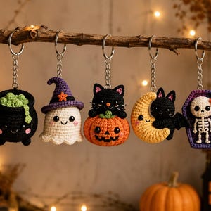 May include: Five crocheted Halloween keychains hanging from a branch. The set includes a black cauldron with green bubbles, a white ghost wearing a purple hat, a black cat on a pumpkin, a black cat on a yellow moon, and a skeleton in a coffin.