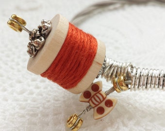 Guitar string bracelet with orange thread spool and silver detail